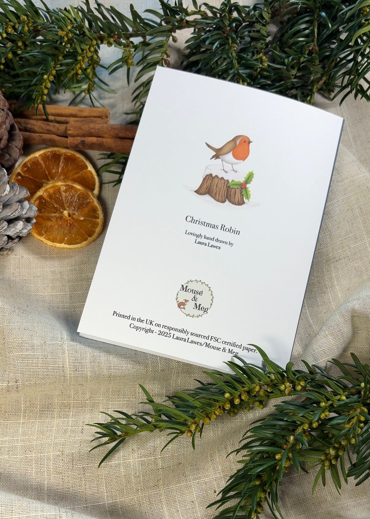 Christmas Card rear with design featuring a robin and holly on a textured surface with greenery and oranges.